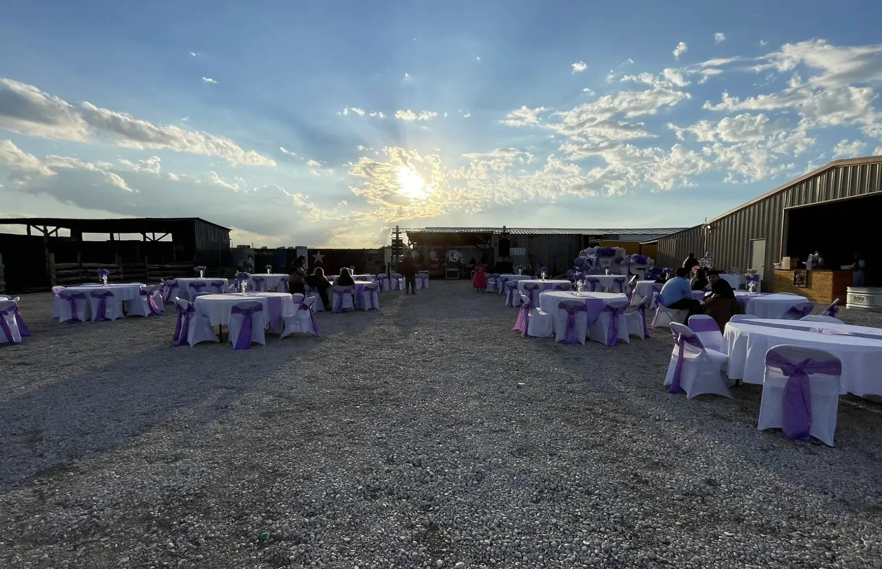 Mesas al aire libre con decoración morada bajo el cielo del atardecer en Rancho 3 Palomas
