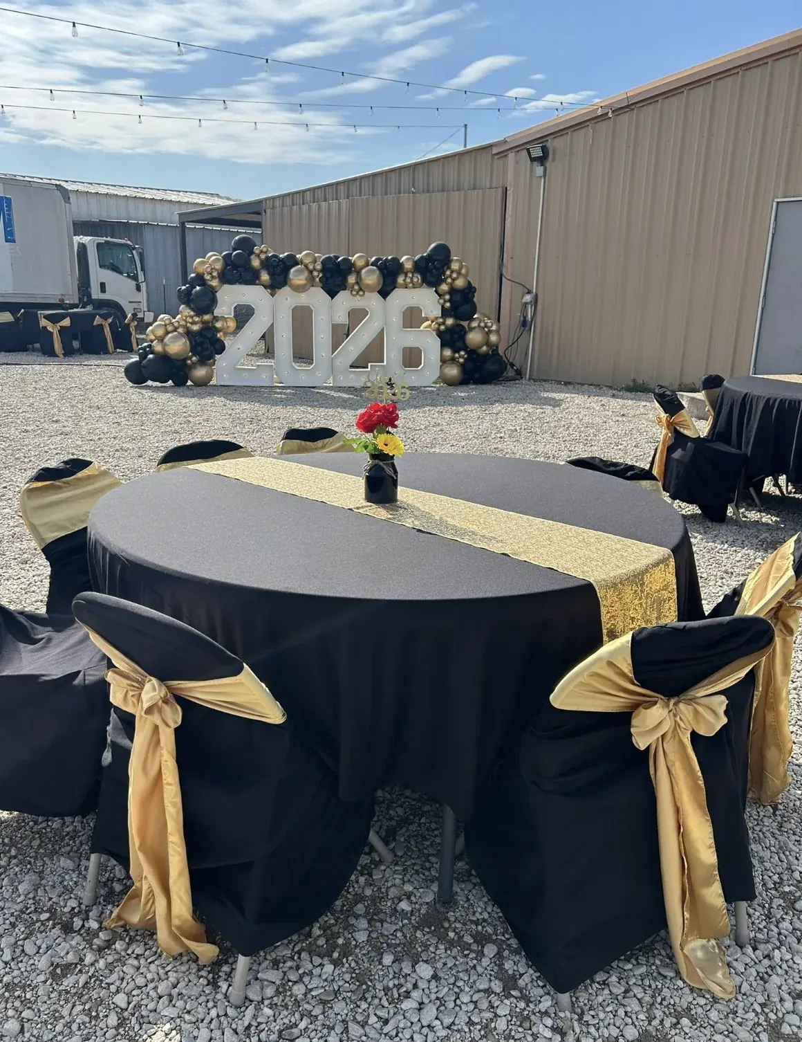 Mesa de celebración en negro y dorado frente al letrero 2026
